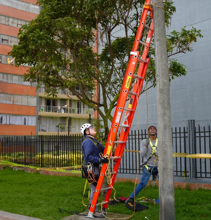 Escalera extensible dieléctrica HORN de fibra de vidrio apoyada en poste de concreto durante trabajo en altura